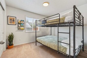 A bunk bed room with a window, a door, and a potted plant. - Stunning 3BR Home-Backyard HOT TUB Oasis-Home Gym (Boise)