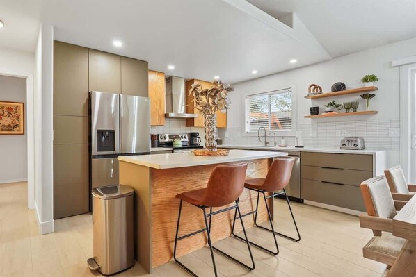 A modern kitchen with a central island, stainless steel appliances, and wooden cabinetry.