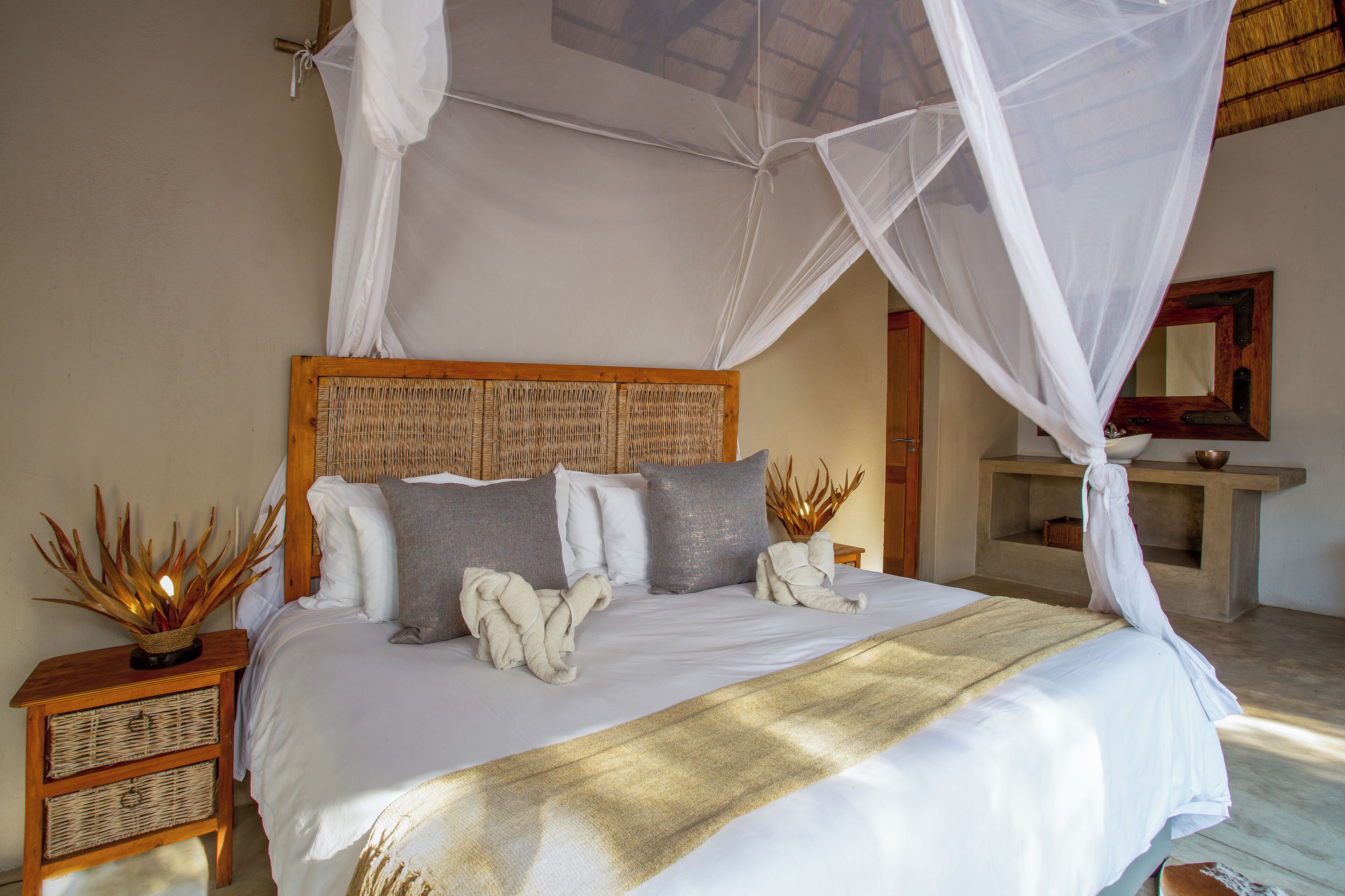 A bed with a canopy, a wooden headboard, and a bedside table with a basket and a lamp.