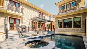 A residential property with a swimming pool, outdoor seating, and a covered patio.