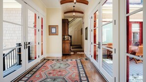 A hallway with a patterned rug, wooden flooring, and glass doors leading to a dining area.