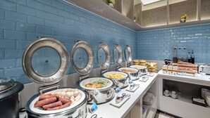 Uma mesa de buffet organizada com várias estações de comida, incluindo diversos pratos e utensílios.