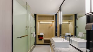 Une salle de bain moderne avec un grand miroir, deux lavabos et une douche à l’italienne.