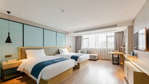 Une chambre d’hôtel avec deux lits, un bureau, une chaise et une télévision.
