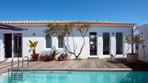 A poolside area with a wooden deck, a pool, and potted plants.