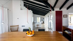 A modern dining area with a wooden table, a bowl of fruit, and a view of a living room with a sofa and a small table.