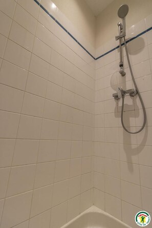 Een badkamer met witte betegelde wanden, een douchekop en een bad.