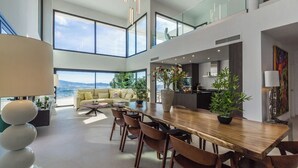 Un amplio salón con una gran mesa de comedor de madera, asientos cómodos y ventanas grandes que ofrecen vistas al exterior.