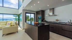 Una cocina moderna con alacenas de madera oscura, una isla grande y vistas a la montaña desde las ventanas.