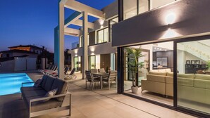 Un espacio exterior moderno con piscina, sillas de descanso y zona de comedor.