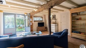 Uma sala de estar aconchegante com um sofá, uma televisão e uma estante de madeira.