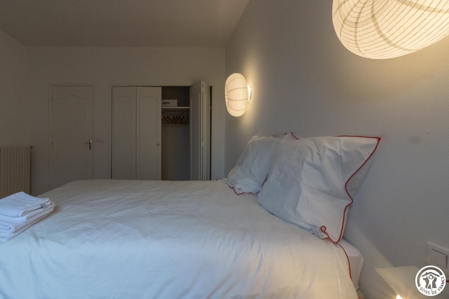 A bedroom with a neatly made bed, a wardrobe, and a closet.