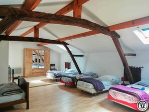 A room with a sloped ceiling, wooden beams, and a skylight. There are three beds with different bedding and a wooden wardrobe. - Chez Antonin - VILLENEUVE LECUSSAN (VILLENEUVE LECUSSAN)