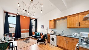 A modern kitchen with wooden cabinets, a built-in oven, and a microwave. - 3 Bed Flat - Sleeps 7 - Parking - Wifi (Birmingham)