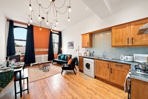 A modern kitchen with wooden cabinets, a built-in oven, and a microwave. - 3 Bed Flat - Sleeps 7 - Parking - Wifi (Birmingham)