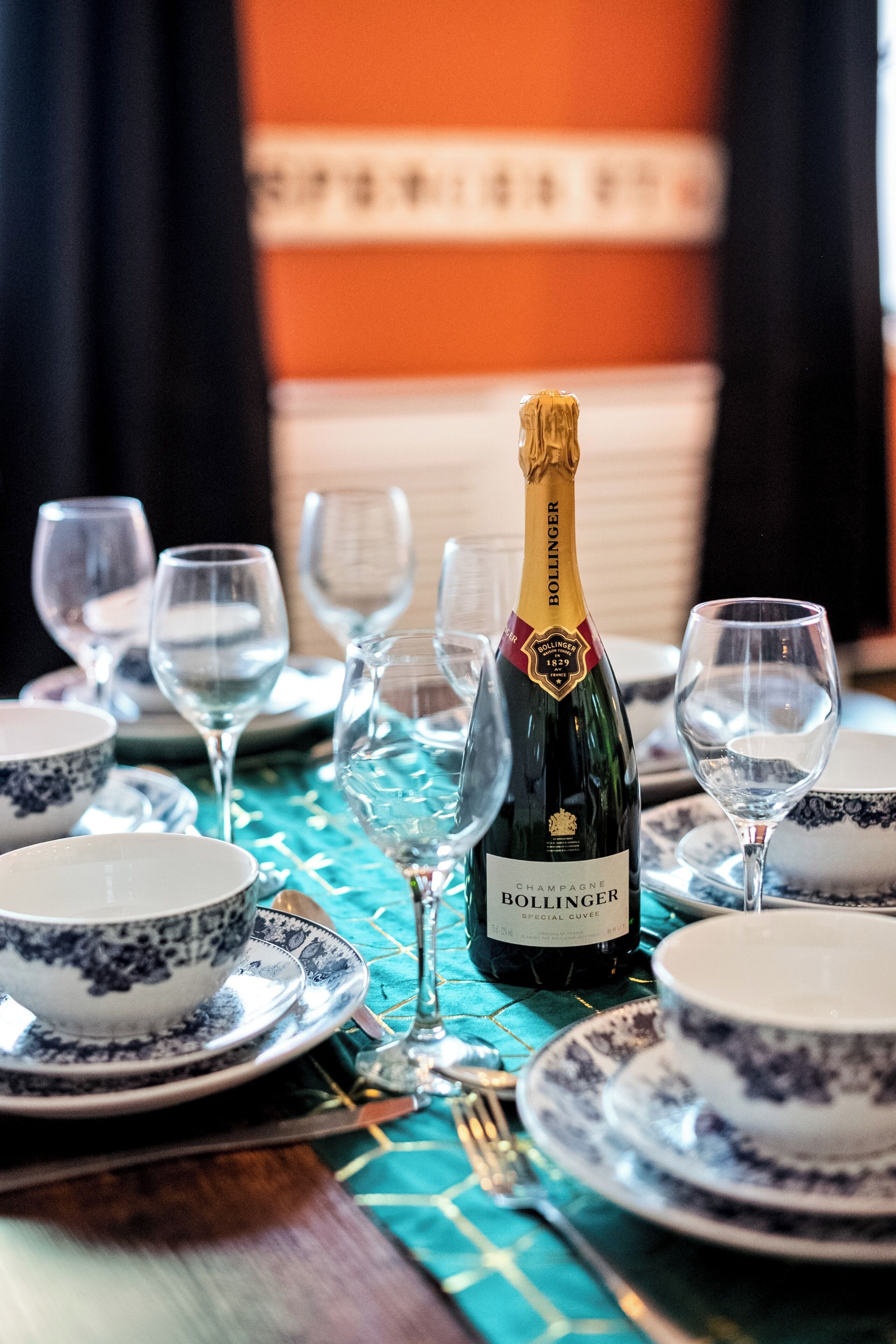 Una mesa dispuesta con una botella de Bollinger, copas y platos.
