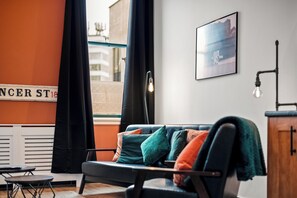 A modern living room with a sofa, a view of the street, and a framed picture on the wall. - 3 Bed Flat - Sleeps 7 - Parking - Wifi (Birmingham)