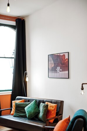 A room with a sofa, a framed picture on the wall, and a window with curtains. - 3 Bed Flat - Sleeps 7 - Parking - Wifi (Birmingham)