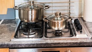 A kitchen with two stainless steel pots on a gas stove, a digital oven control panel, and a stainless steel oven door. - 3 Bed Flat - Sleeps 7 - Parking - Wifi (Birmingham)