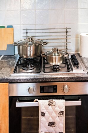 A kitchen with two stainless steel pots on a gas stove, a digital oven control panel, and a stainless steel oven door. - 3 Bed Flat - Sleeps 7 - Parking - Wifi (Birmingham)