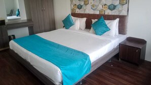 A hotel room with a bed, a wardrobe, a bedside table, and a decorative wall. - Arristo Resorts & Club (Ahmedabad)