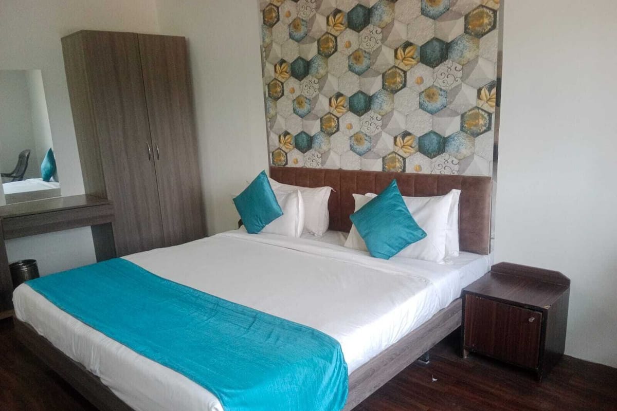Una cama bien hecha con ropa de cama blanca y aguamarina, un cabecero de madera y una mesita de noche pequeña.