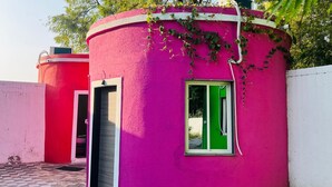A pink building with a green window and a door. - Arristo Resorts & Club (Ahmedabad)