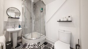 A modern bathroom with a glass-enclosed shower, a white sink, and a toilet.
