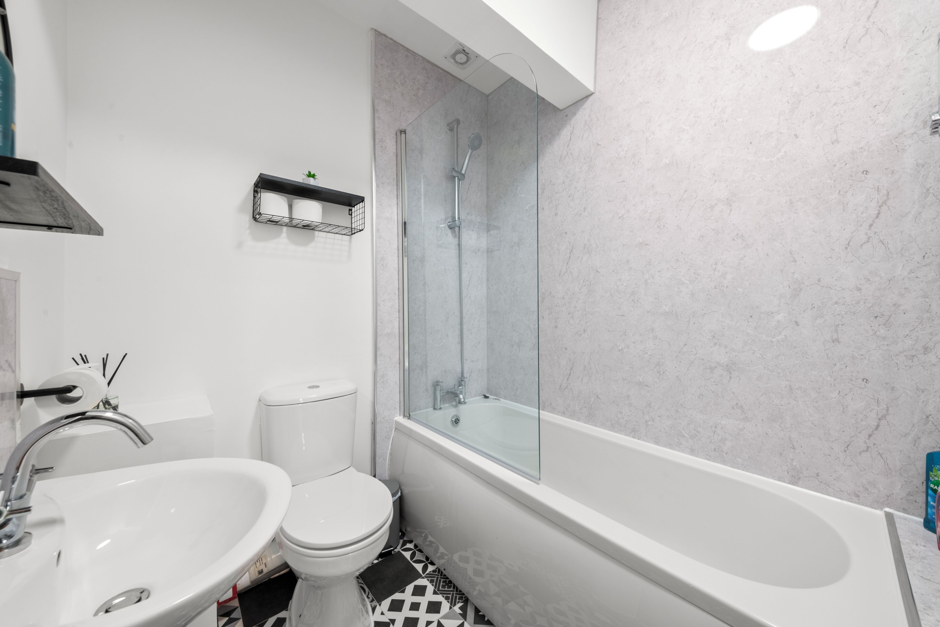 Un baño moderno con lavamanos, inodoro y ducha con cerramiento de vidrio.