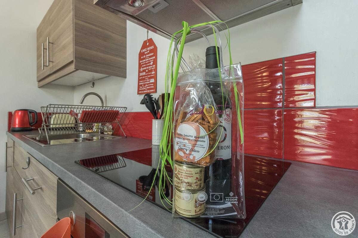Een keuken met een roestvrijstalen aanrecht, een rode waterkoker, een afdruiprek en een fles mosterd.