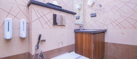 Ein Badezimmer mit Toilette, Waschbecken, Spiegel, Handtuchspender und Dusche.