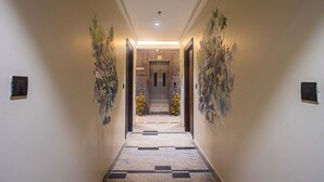 A hallway with a marble floor, two potted plants, and a door with a number sign. - Hotel Lords Valley Rishikesh (Rishikesh)