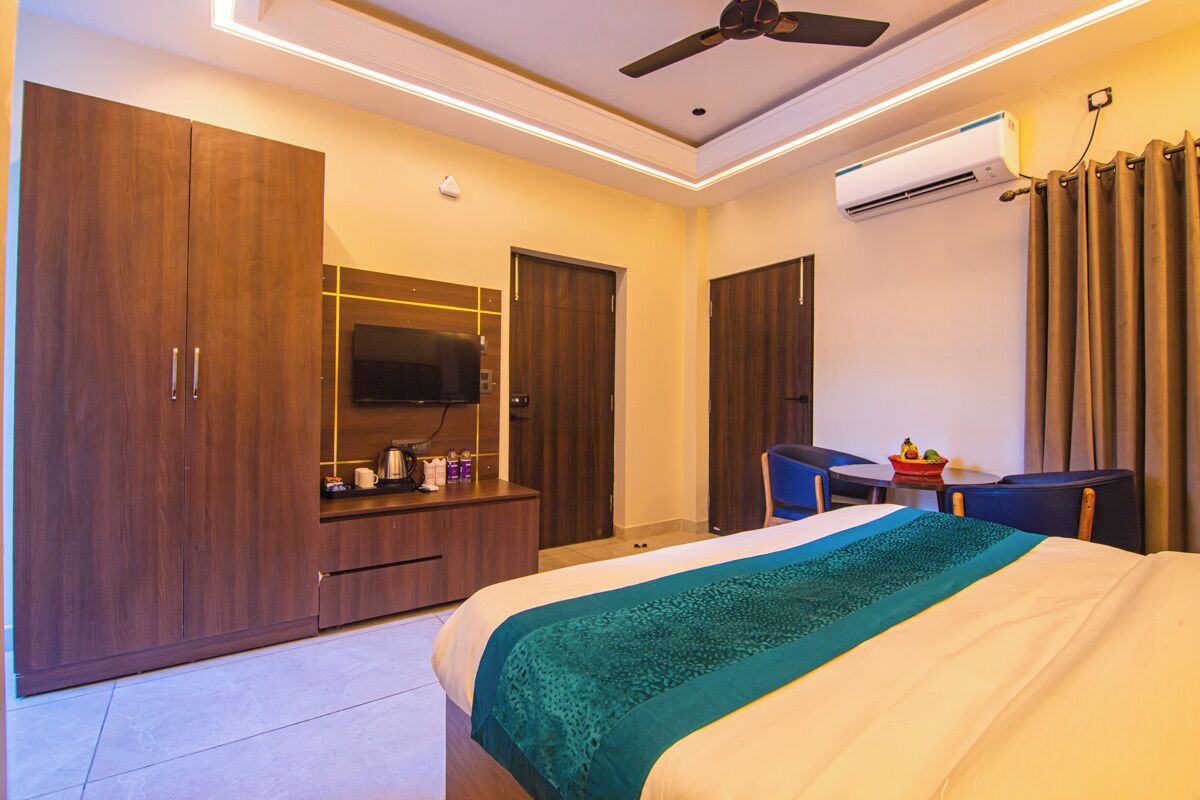 A hotel room with a bed, a desk, a TV, and a wardrobe.
