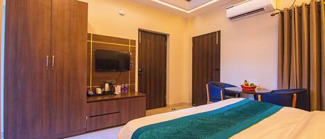 Habitación de hotel con cama, escritorio, televisión y armario.