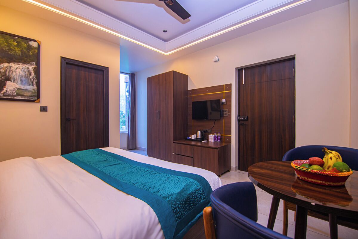 Habitación de hotel con cama, escritorio con silla, televisor y frutero.