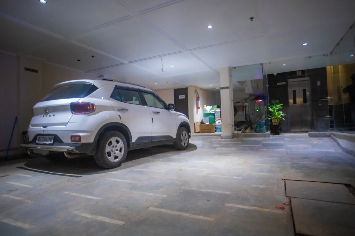 A white SUV parked in a spacious, well-lit indoor area with a tiled floor and a modern architectural design.