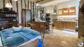 Une cuisine rustique avec des poutres en bois, une table à manger avec des chaises et un îlot de cuisine doté d  ’un évier et d’appareils électroménagers.