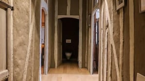 Un couloir doté d’un plancher en bois, de murs en briques apparentes et d’un luminaire encastré au plafond.