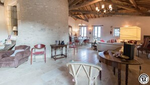 Un vaste salon doté d’un haut plafond en bois, un coin repas avec une table et des chaises, et un espace salon confortable avec un canapé et des fauteuils.
