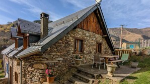Ein Steinhaus mit geneigtem Dach, einer Satellitenschüssel und einem kleinen Außenbereich mit Tisch und Stühlen.