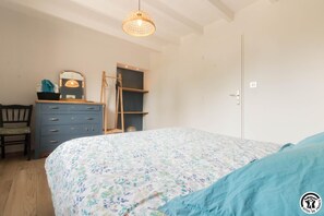 Ein Schlafzimmer mit Bett, Kommode, Stuhl und einer Pendelleuchte.