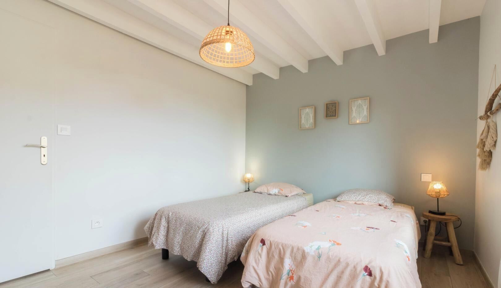 Un dormitorio con dos camas, una lámpara colgante y una mesita con lámpara.