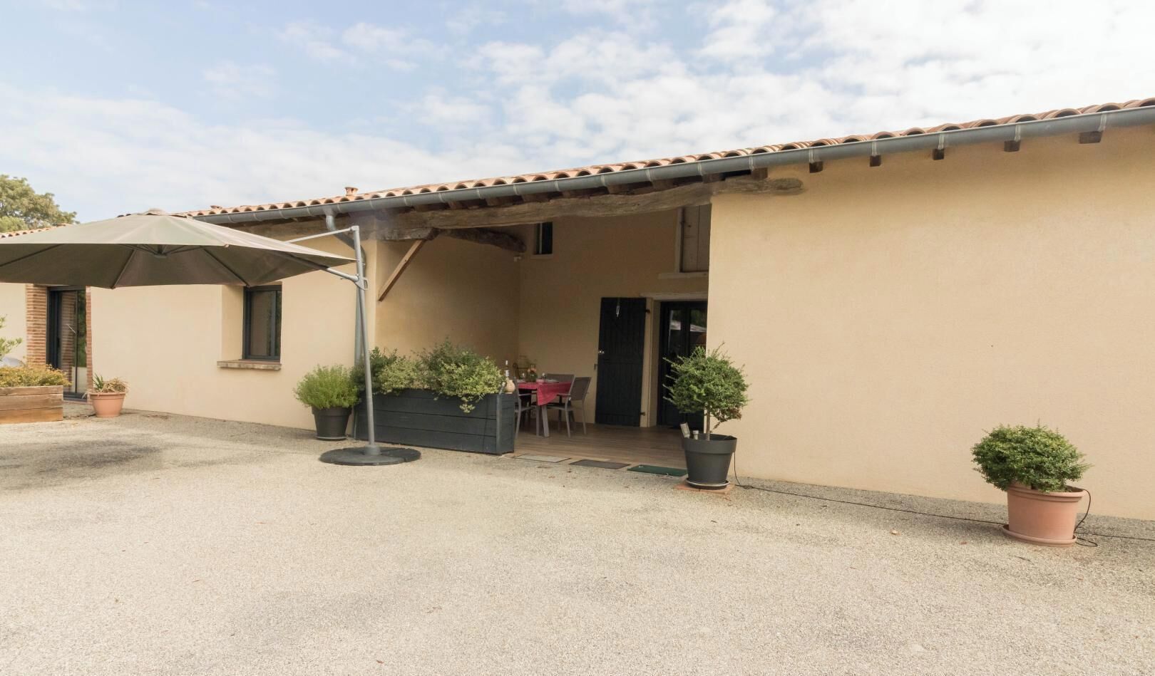 Un bâtiment doté d’un patio couvert, d’un espace extérieur aménagé pour s’asseoir et de plantes en pot.