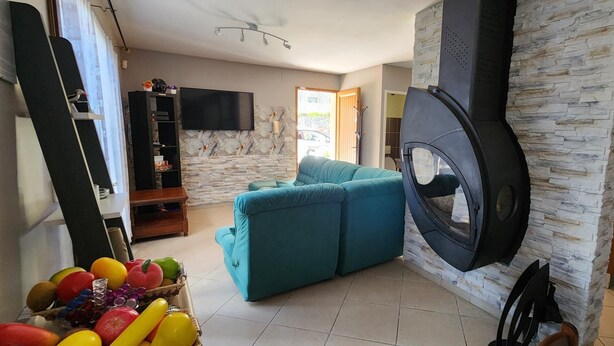 Ein Wohnzimmer mit einer Couch, einer Steinwand, einem Kamin und einem Fernseher.