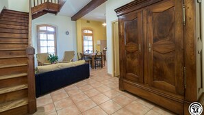 A spacious room with a wooden staircase, a large wardrobe, and a dining area with a table and chairs.