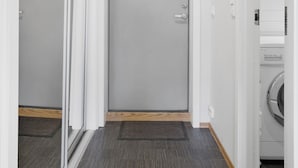 A hallway with a closed door, a washing machine, and a light fixture on the ceiling.