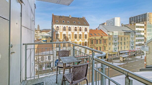 A balcony with metal railings, a table, and two chairs.