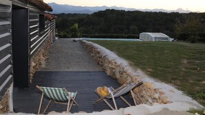 Un patio con dos sillones a rayas, un muro de piedra y vistas a montañas.