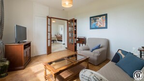 Una sala de estar con televisor, sofá, mesa de centro y estantería.