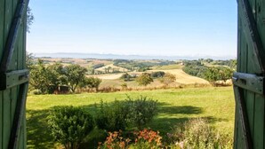 A view from a green wooden structure overlooking a rural landscape with fields and distant mountains.